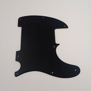 Może przedstawiać: Czarny pickguard do gitary z wieloma otworami na śruby.