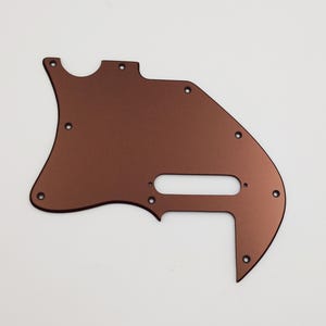 May include: A copper-colored guitar pickguard with multiple screw holes.