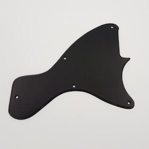 Puede incluir: Golpeador de guitarra de plástico negro con bordes redondeados y varios agujeros para tornillos.