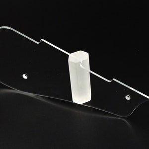 Puede incluir: Un soporte para p&uacute;as de guitarra de pl&aacute;stico transparente con un peque&ntilde;o soporte de pl&aacute;stico transparente. El soporte tiene una forma curva y varios agujeros para guardar p&uacute;as de guitarra.
