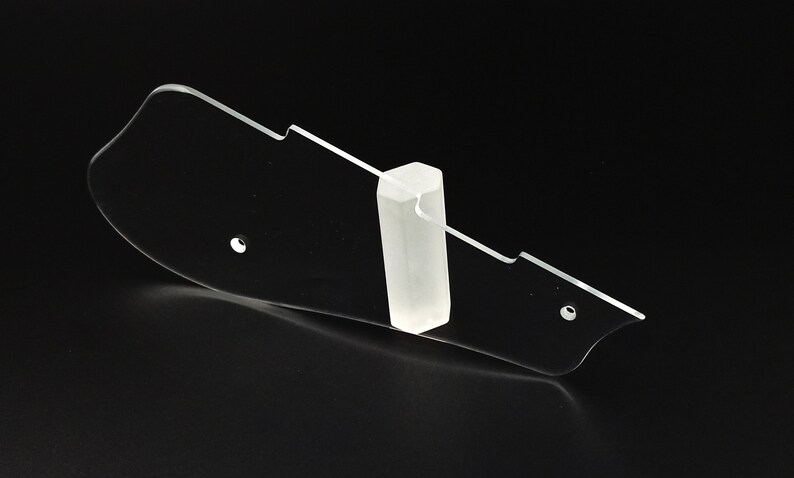 Puede incluir: Un soporte para p&uacute;as de guitarra de pl&aacute;stico transparente con un peque&ntilde;o soporte de pl&aacute;stico transparente. El soporte tiene una forma curva y varios agujeros para guardar p&uacute;as de guitarra.