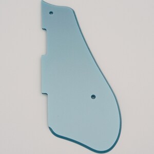 May include: A light blue plastic guitar pickguard with two small holes.