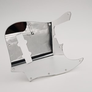 Może przedstawiać: Chromowany pickguard do gitary basowej. Pickguard ma wycięcie na przetwornik i gałkę regulacyjną.