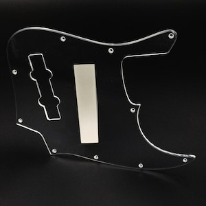 Puede incluir: Golpeador transparente de plástico para un bajo. El golpeador tiene un recorte para las perillas de control y una abertura rectangular para una pastilla.