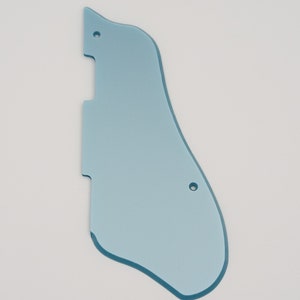 May include: A light blue guitar pickguard with a unique shape, featuring two pre-drilled holes for mounting. The pickguard has a smooth, glossy finish and is designed to protect the guitar's body from scratches.