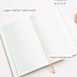 May include: Open notebook with 224 lined pages and a vegan leather hard cover. It measures 8.5" x 5.5" and includes a ribbon bookmark. The text "hot stamping add-on available" is also visible.