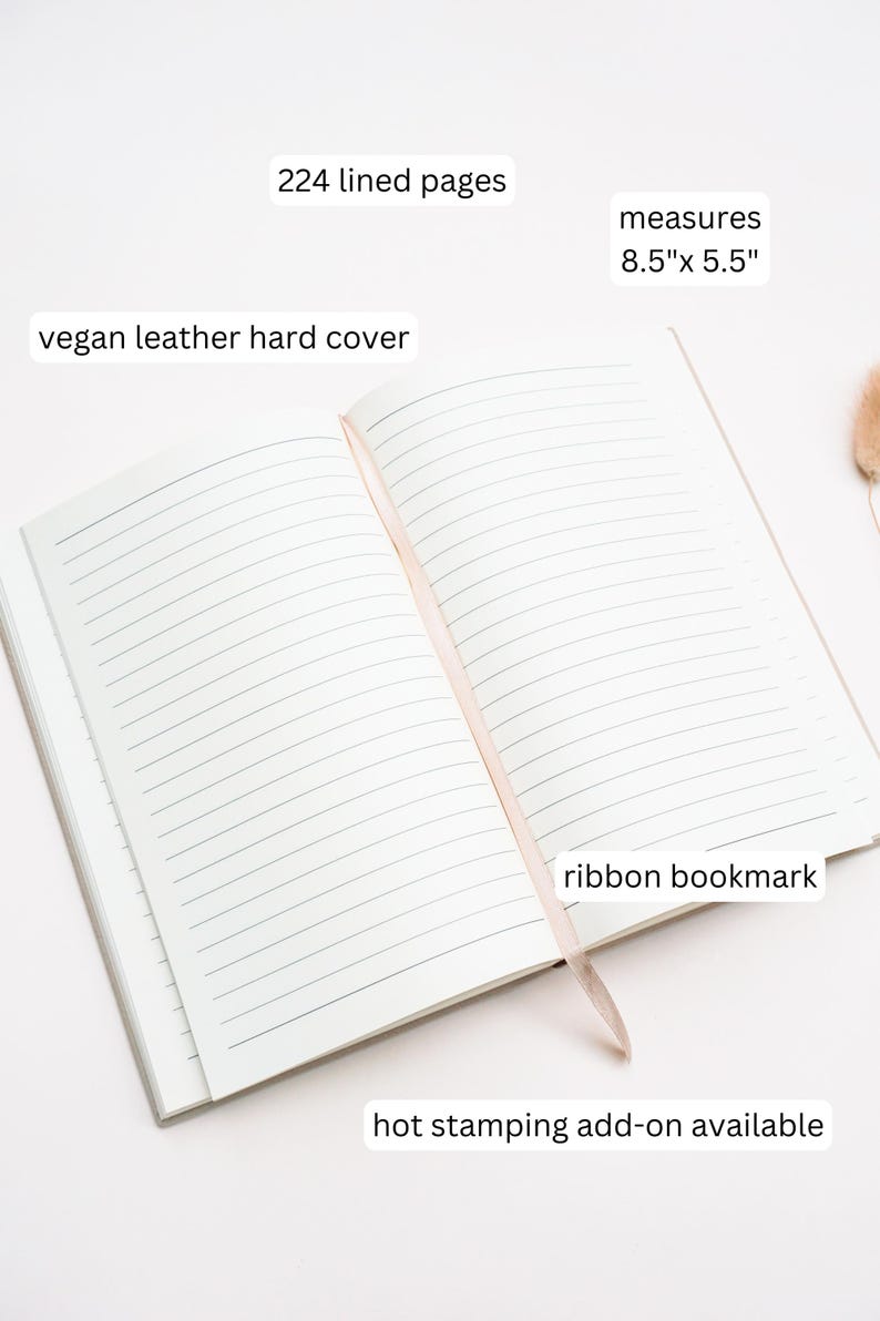 May include: Open notebook with 224 lined pages and a vegan leather hard cover. It measures 8.5" x 5.5" and includes a ribbon bookmark. The text "hot stamping add-on available" is also visible.