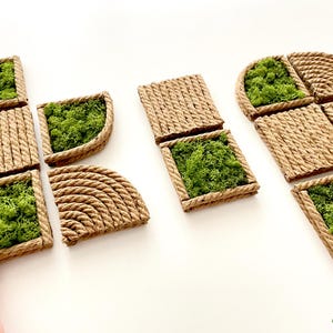 May include: A collection of modular wall tiles featuring natural green moss encased in frames made of coiled tan rope. The set includes square and quarter-circle shapes with textured rope surfaces and vibrant green preserved moss inserts.