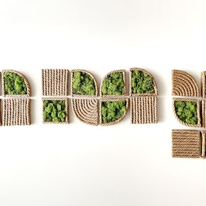 May include: A collection of modular wall art pieces featuring a combination of natural green preserved moss and tan rope arranged in geometric patterns. The set includes square and quarter-circle shapes with textured rope borders and centers.