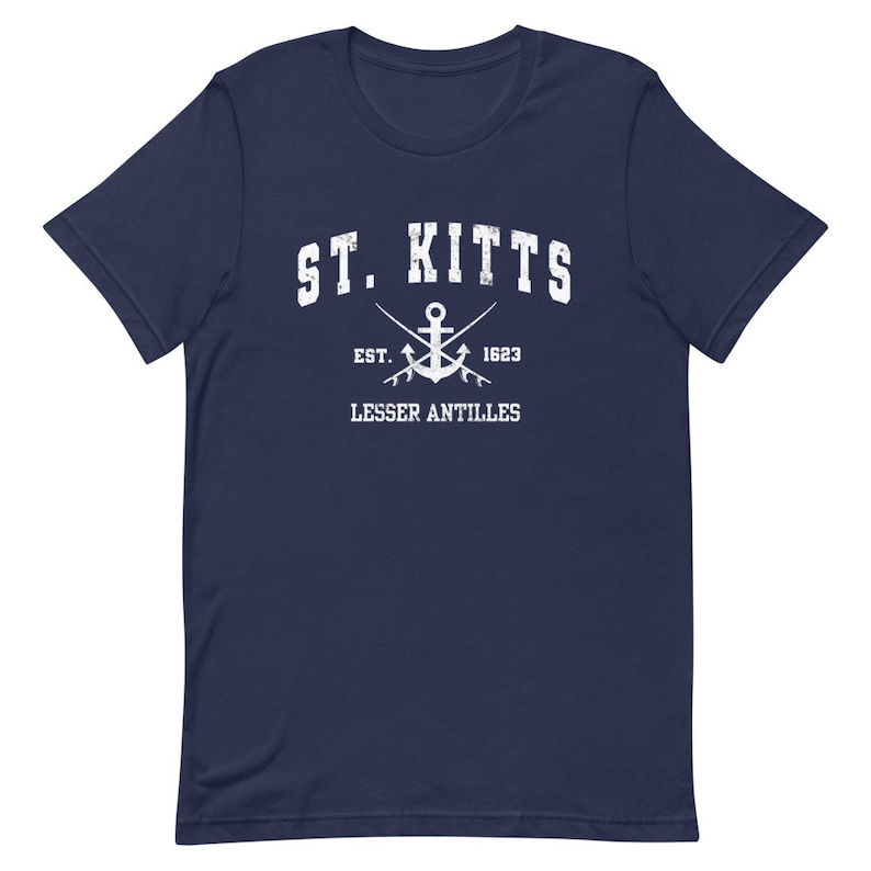May include: A navy blue t-shirt with a white graphic design. The graphic features the text "ST. KITTS" in a vintage style font, an anchor with crossed oars, and the text "EST. 1623 LESSER ANTILLES".