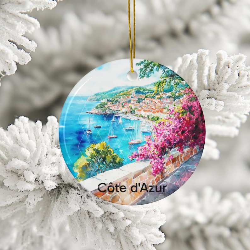 Peut inclure: Une d&eacute;coration en c&eacute;ramique ronde orn&eacute;e d'une peinture aquarelle vibrante de la c&ocirc;te d'Azur, avec des eaux bleues, des voiliers, un village &agrave; flanc de colline et des fleurs de bougainvilliers rose vif. Le texte C&ocirc;te d'Azur est inscrit en bas.