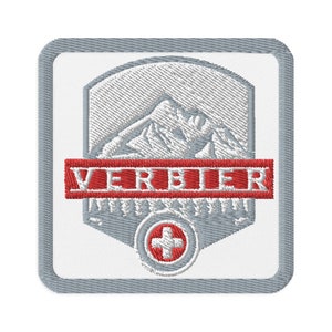 Puede incluir: Parche blanco bordado con un diseño de cordillera gris y la palabra "VERBIER" en rojo. Una cruz roja está en el centro del parche.