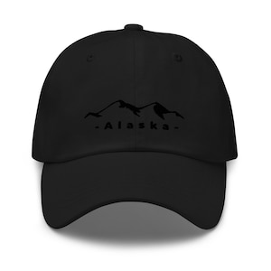 May include: Black baseball cap with a black mountain range graphic and the text "Alaska" in white.