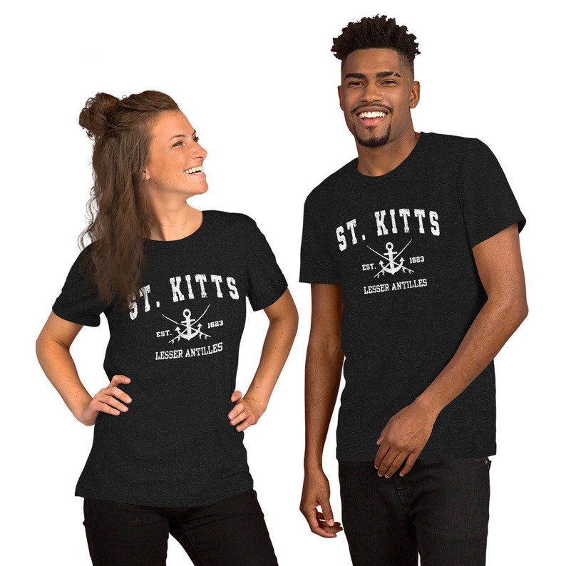 May include: Two people wearing black t-shirts with a white graphic design. The design features the text "ST. KITTS", an anchor, and the text "EST. 1623 LESSER ANTILLES".