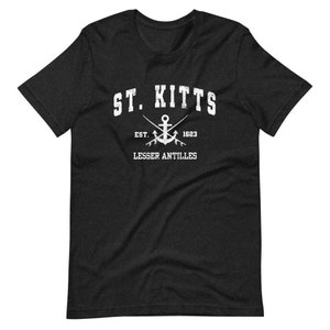 May include: A black t-shirt with a white graphic design that says "ST. KITTS" with an anchor and crossed fishing rods underneath. The text "EST. 1623" and "LESSER ANTILLES" are also included in the design.