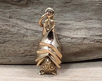 May include: A gold-colored bat charm hanging upside down. The bat is detailed with wings and a face.