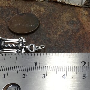 May include: Silver corkscrew charm measuring approximately 1 inch in length. The charm is detailed with a corkscrew design and a heart-shaped loop for attaching to a necklace or bracelet.
