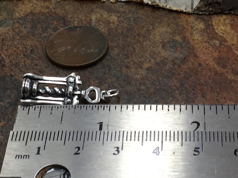 May include: Silver corkscrew charm measuring approximately 1 inch in length. The charm is detailed with a corkscrew design and a heart-shaped loop for attaching to a necklace or bracelet.
