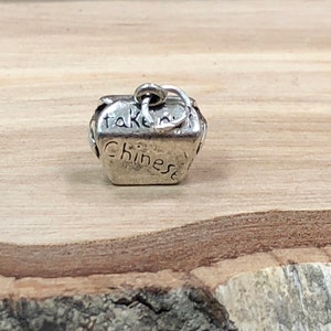 May include: Silver charm in the shape of a Chinese takeout container with the words "take out" and "Chinese" engraved on the sides.