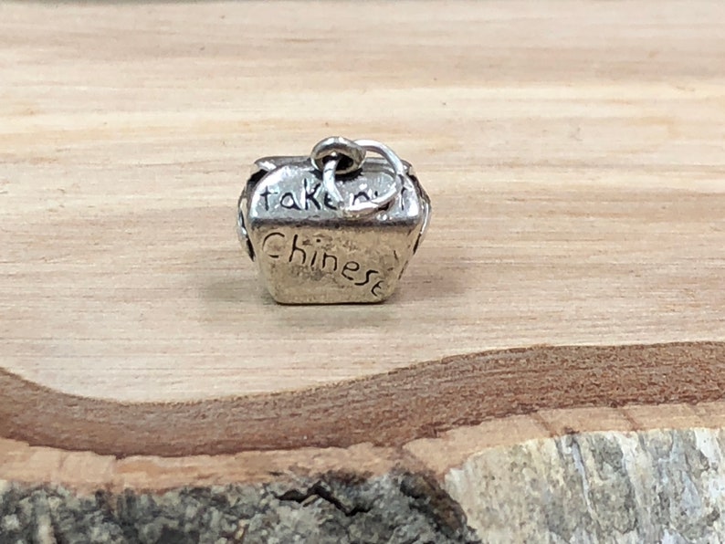 May include: Silver charm in the shape of a Chinese takeout container with the words "take out" and "Chinese" engraved on the sides.