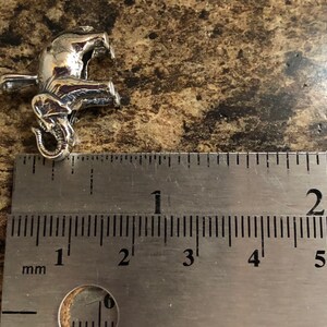 May include: Silver elephant charm pendant measuring approximately 2 cm in length. The charm is detailed with a textured surface and a curled trunk.