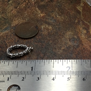 Pu&ograve; includere: Un braccialetto a catena d'argento con un design delicato e intricato. Il braccialetto ha un diametro di circa 2,5 cm ed &egrave; misurato con un righello.