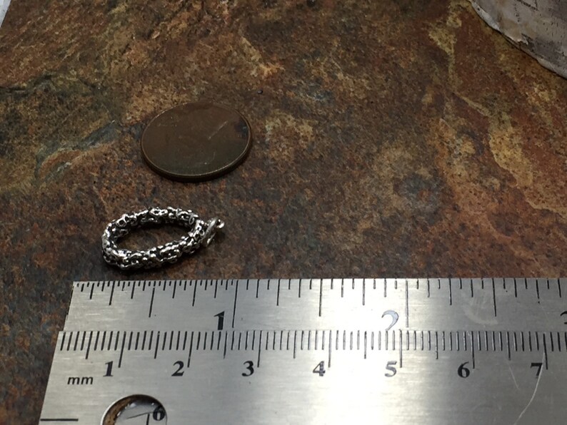 Pu&ograve; includere: Un braccialetto a catena d'argento con un design delicato e intricato. Il braccialetto ha un diametro di circa 2,5 cm ed &egrave; misurato con un righello.