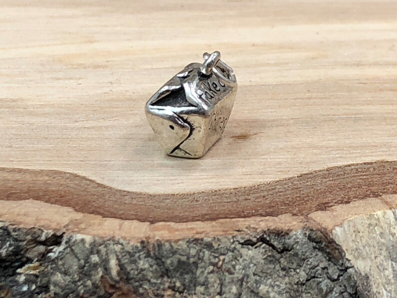 May include: Silver charm in the shape of a takeout container with the word "Takeout" on the side.