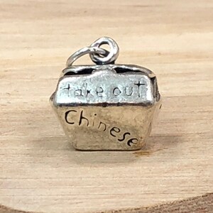 May include: Silver charm shaped like a Chinese takeout container with the words "take out Chinese" engraved on it.