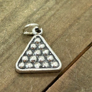 May include: Silver charm shaped like a triangle with a raised design of a pool ball rack.