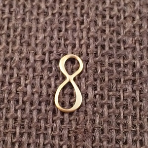 May include: A gold-colored infinity symbol charm. The charm is made of metal and has a smooth, polished finish.