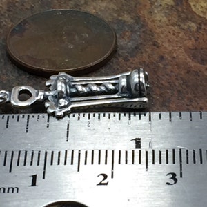 May include: Silver corkscrew charm measuring 1 inch in length. The charm is detailed with a twisted metal design and a loop for attaching to a necklace or bracelet.