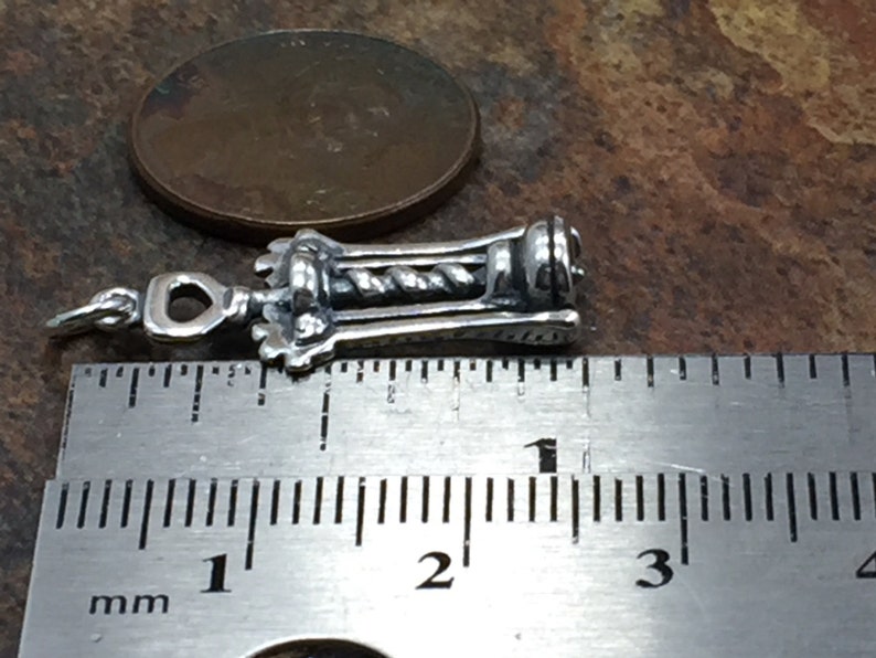 May include: Silver corkscrew charm measuring 1 inch in length. The charm is detailed with a twisted metal design and a loop for attaching to a necklace or bracelet.