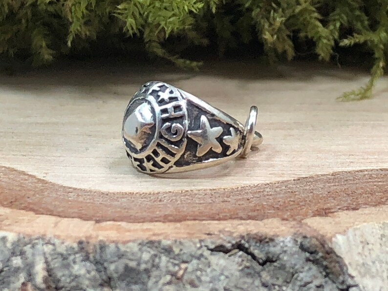 May include: A silver charm in the shape of a class ring with the word "HIGH" engraved on the side and three stars on the band.