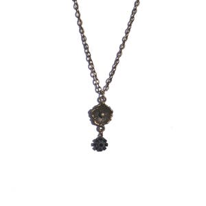 May include: A silver chain necklace with a gold flower charm and a smaller black flower charm.