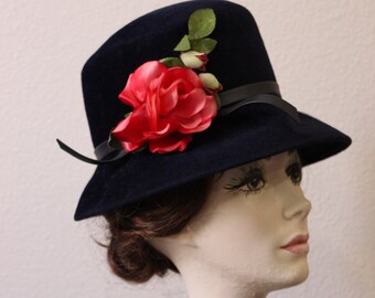 May include: A navy blue felt hat with a wide brim and a red rose embellishment.