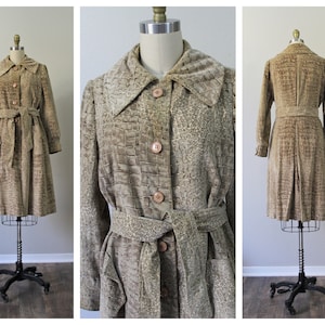 Puede incluir: Un abrigo marrón de imitación de ante con estampado de piel de cocodrilo y un cinturón a juego. El abrigo tiene una silueta larga y de línea A y un cuello.