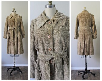 May include: A brown faux-suede coat with a crocodile print pattern and a matching belt. The coat has a long, A-line silhouette and a collar.