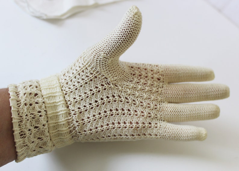 May include: A pair of off-white crocheted gloves with a delicate pattern. The gloves are made of a lightweight, breathable fabric and have a comfortable fit.