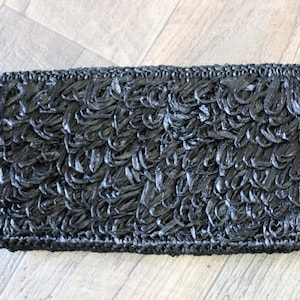 May include: Black woven clutch purse with a fringe design.