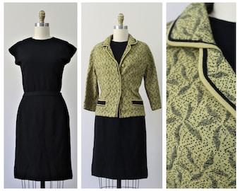 May include: A black knit dress with a matching cardigan. The cardigan has a green and black geometric pattern and black trim.