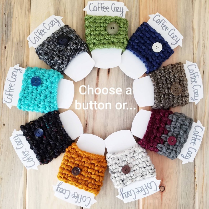 May include: Ten crocheted coffee cup cozies in various colors, including teal, green, brown, black, white, and mustard yellow. Each cozy has a button on the front. The cozies are arranged in a circle on a wooden surface. Choose a button or...