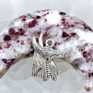 May include: A crescent moon shaped piece of white and pink crystal with a silver Anubis pendant charm.