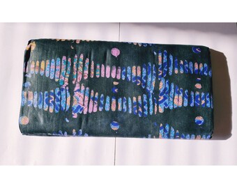 May include: A dark green fabric with a repeating pattern of blue, pink, and yellow lines and circles.