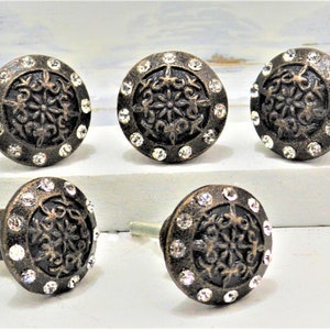 May include: Set of six antique bronze cabinet knobs with a decorative floral design and clear crystal rhinestones.