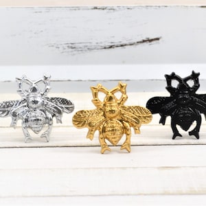 May include: Three bee-shaped metal drawer pulls in silver, gold, and black.