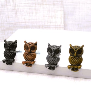 May include: Four decorative owl-shaped cabinet knobs in varying metallic finishes: black, bronze, silver, and gold. Each owl is perched on a branch, adding a touch of nature-inspired charm to furniture or decor.