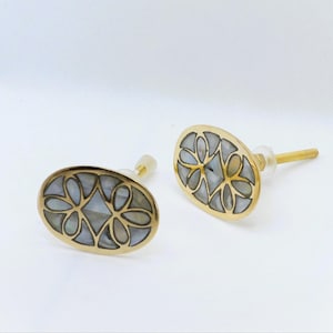 May include: Two oval cabinet knobs with a gold finish and inlaid mother-of-pearl floral design. The knobs have a screw post for easy installation. These decorative knobs are perfect for adding a touch of elegance to furniture.
