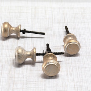 May include: Three antique-style cabinet knobs with a distressed gold finish. Each knob has a rounded shape with a black threaded bolt and washer for installation. These decorative knobs are ideal for furniture restoration or adding a vintage touch.