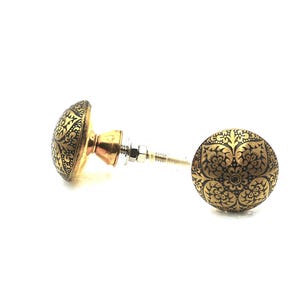 May include: Two decorative cabinet knobs with a gold finish and intricate black floral patterns. The knobs have a round shape and are made of metal. The hardware includes a screw and nut for installation.